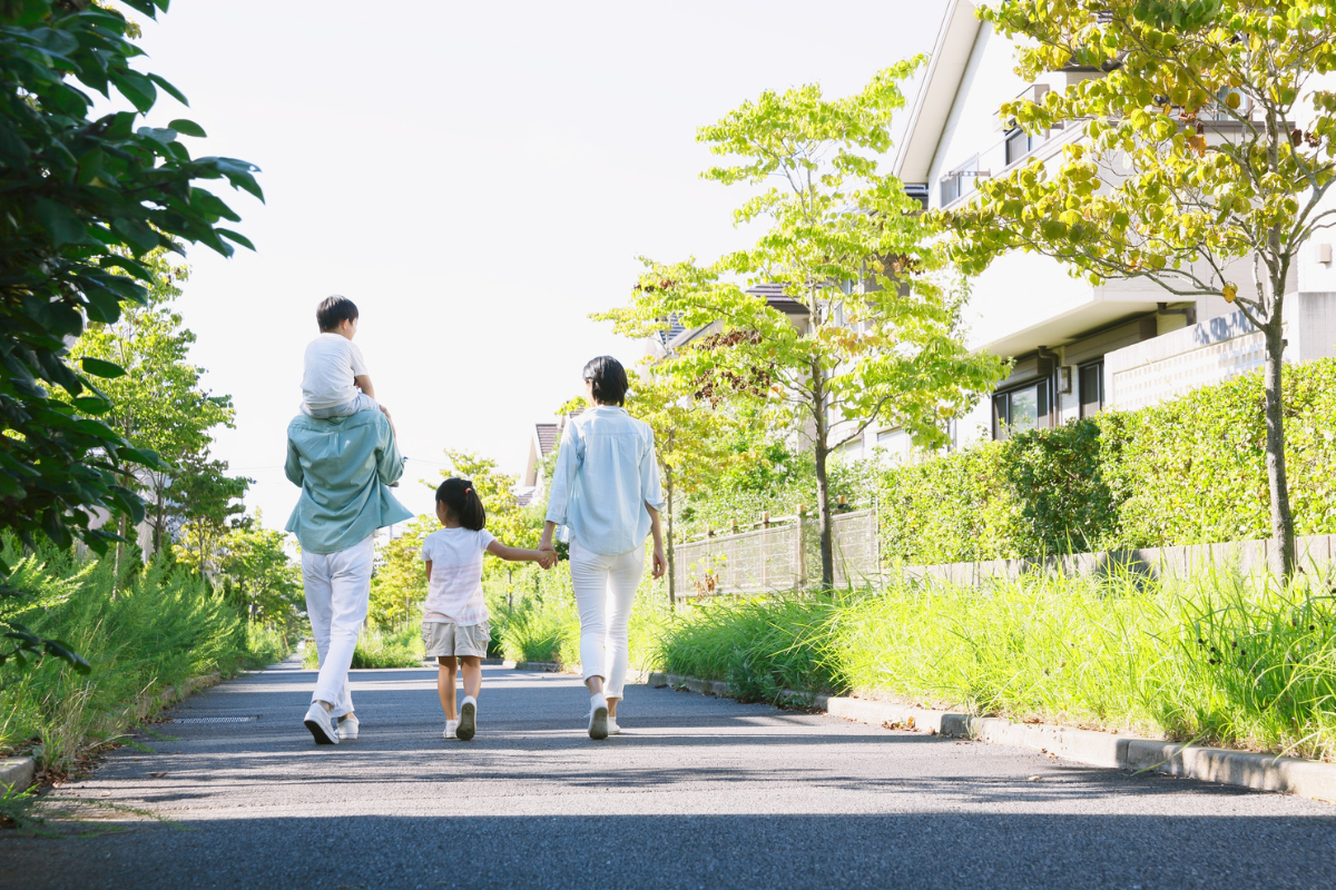 緑の多い住宅街を家族で歩く様子